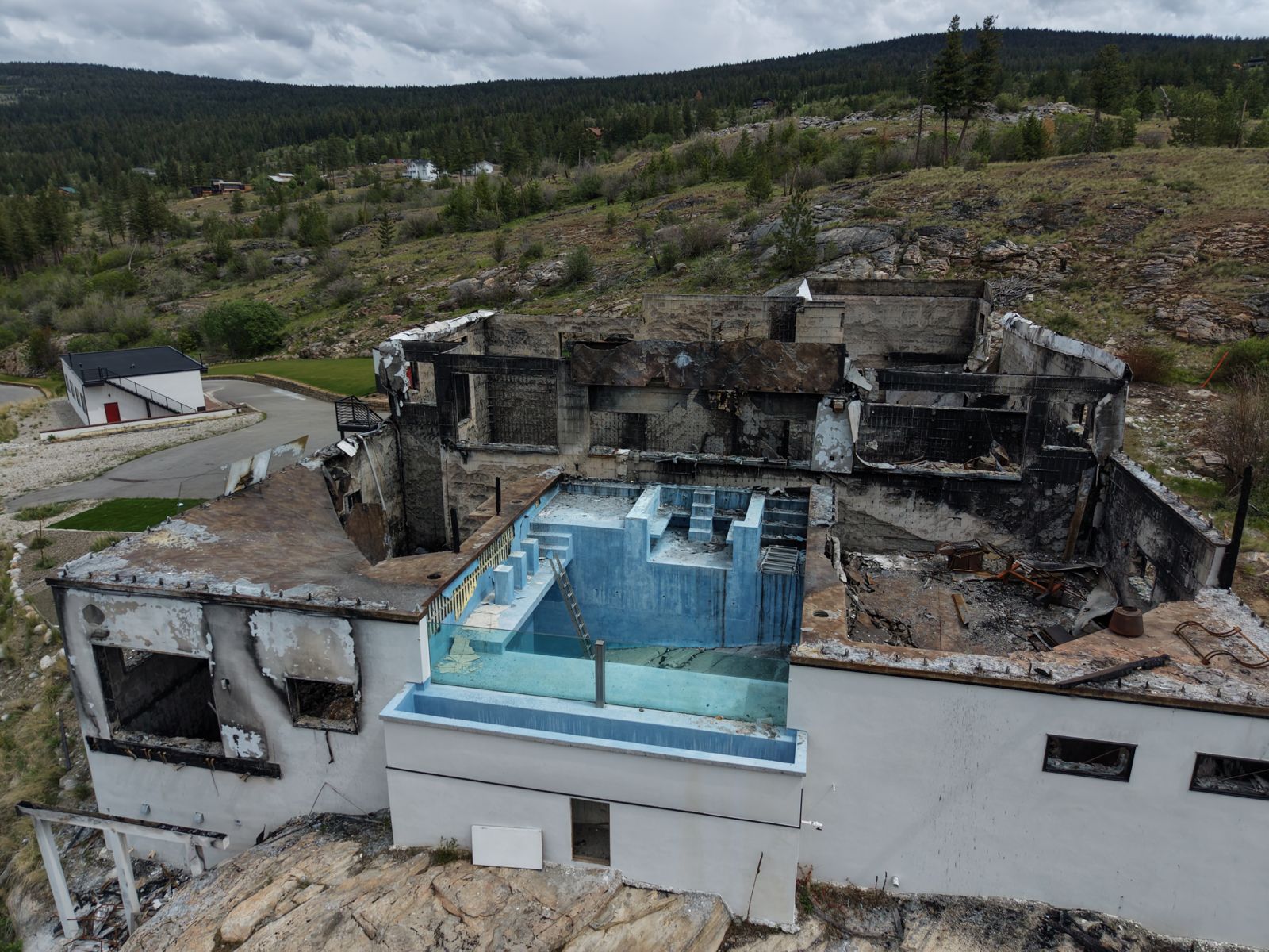 A large hillside home in the South Okanagan burned down to its concrete walls, with an empty rooftop pool in the middle